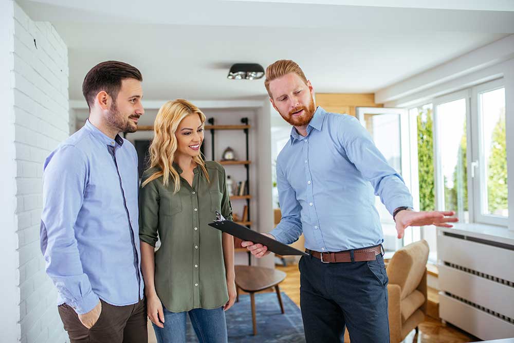 Representante inmobiliario enseñando a unos clientes una nueva vivienda