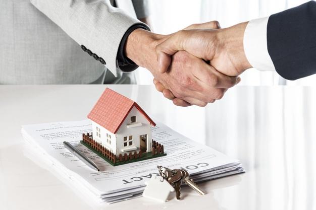 Representante inmobiliario y cliente cerrando la compra de un inmueble mediante un apretón de manos