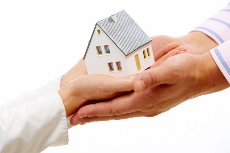 Persona entregando una casa en forma de maqueta a un cliente