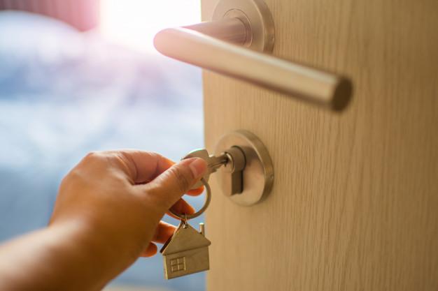Persona abriendo una puerta de una vivienda con una llave