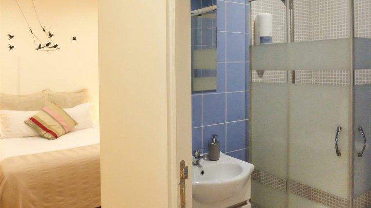 Habitación de una casa donde al lado se puede apreciar un baño con una ducha