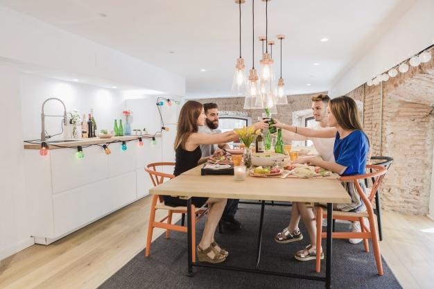 Grupo de parejas reunidos en una mesa brindando felices