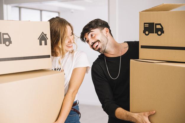 Pareja matrimonial cargando cajas para inciar su mudanza y traslado a su nuevo hogar soñado