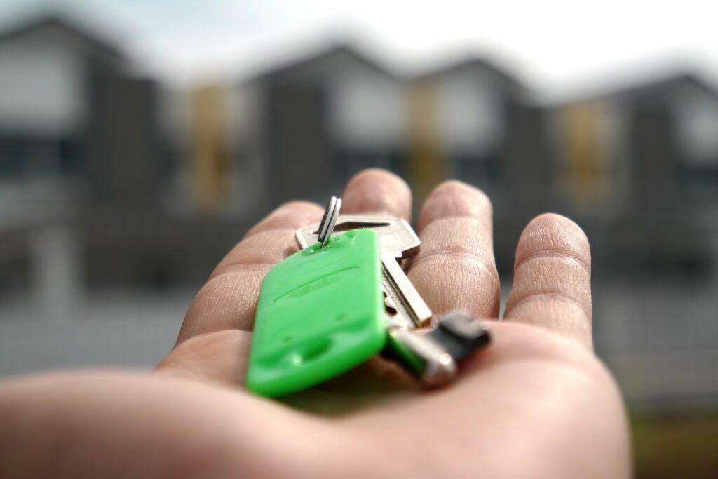 Persona con la mano estirada sosteniendo unas llaves de un nuevo hogar