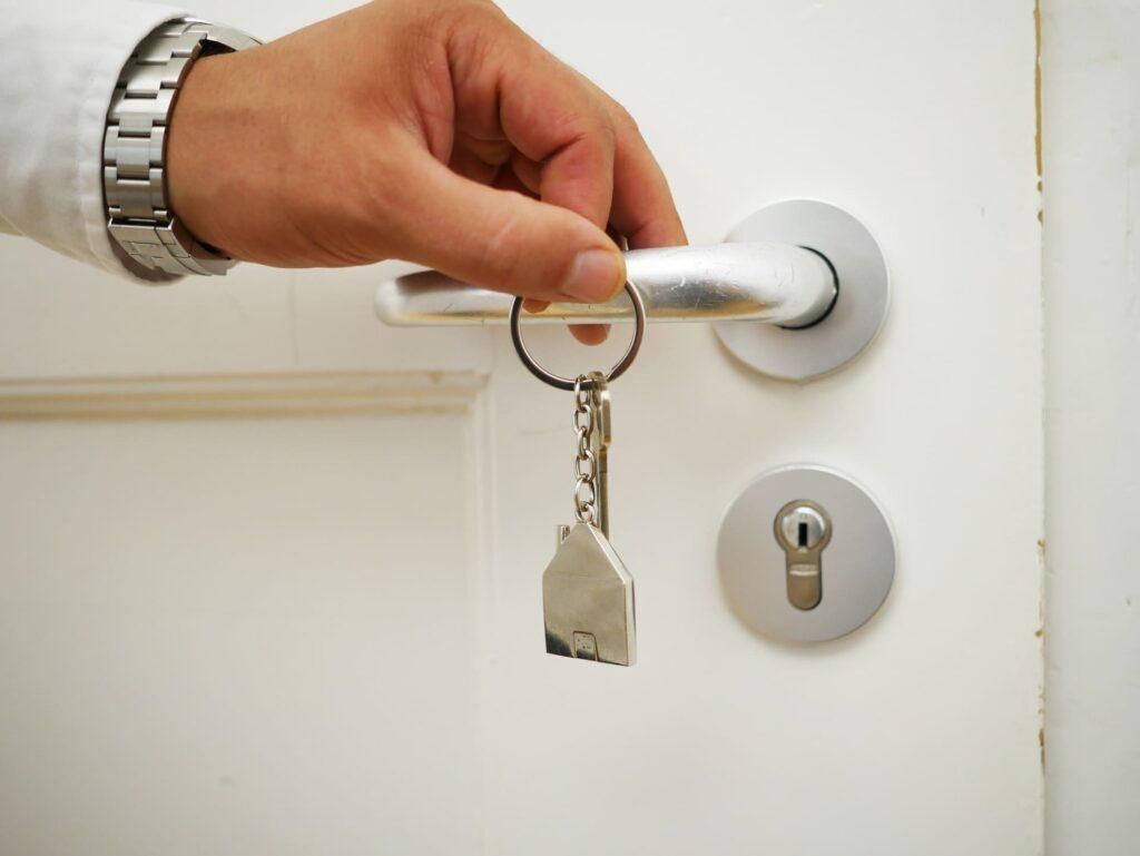 Persona abriendo la puerta mientras sostiene unas llaves para abrir la puerta