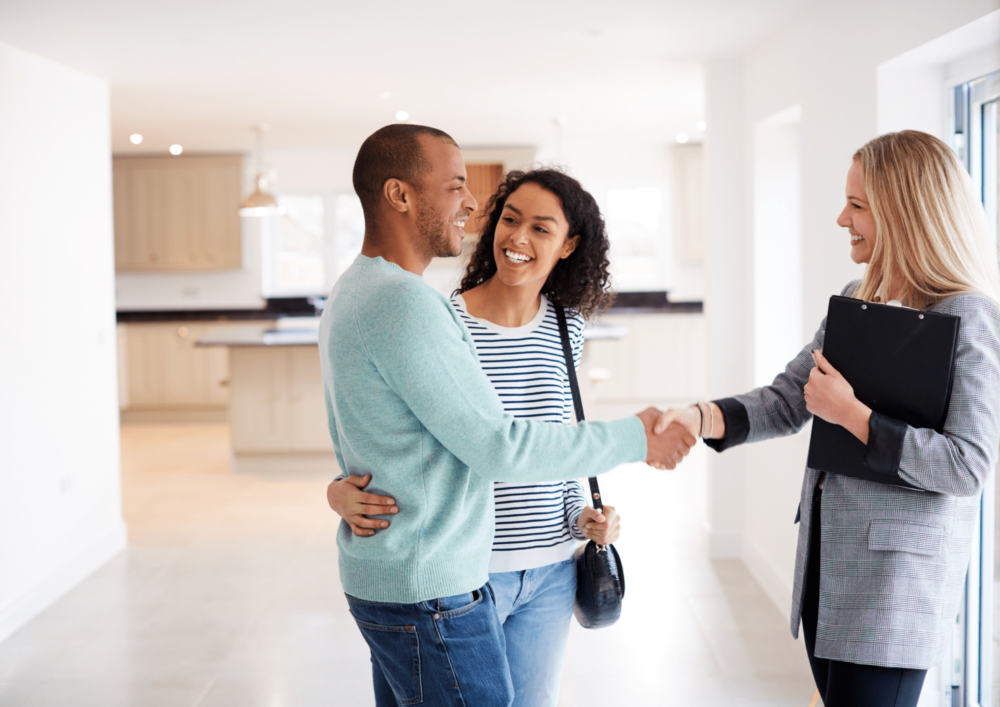 Pareja mostrando su felicidad y satisfacción con su Representante Inmobiliaria por la venta de su piso.