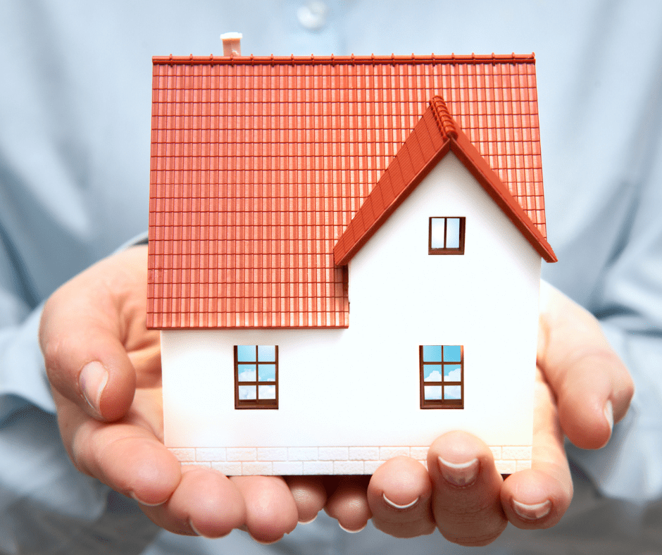 Persona sosteniendo en sus manos una casa en forma de maqueta