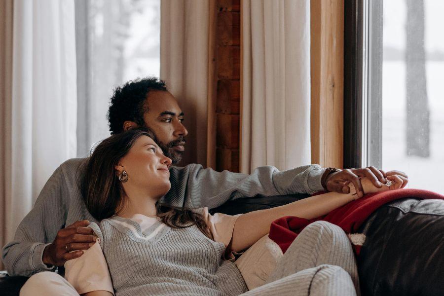 pareja cómplice mira por la ventana desde el interior